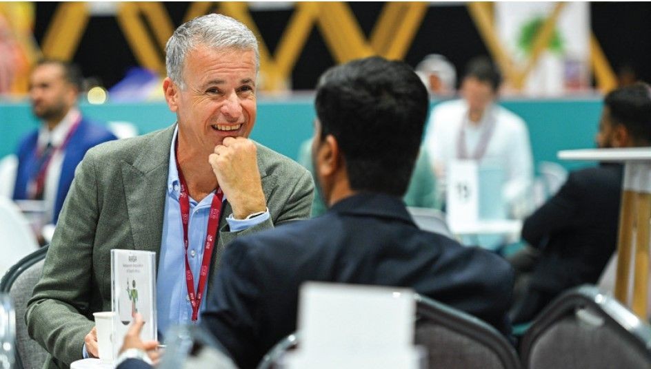 Two individuals seated at a table, engaged in conversation during a business networking event.